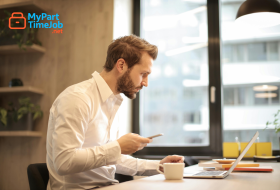 Parent using laptop at home with child nearby.