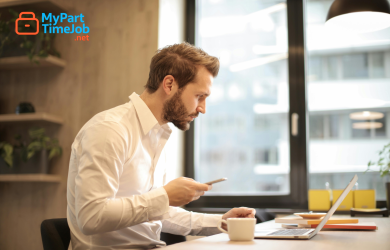 Parent using laptop at home with child nearby.