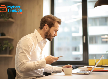 Parent using laptop at home with child nearby.